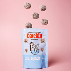 Datekin coconut round date balls packaging with balls spilling out on a pink background