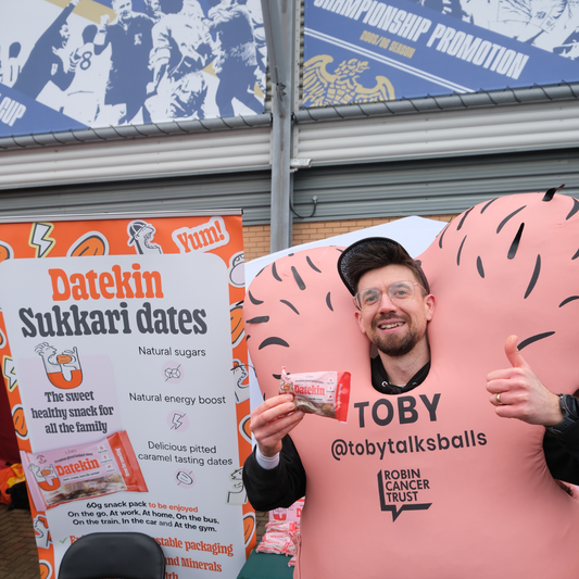 Toby Freedman of The Robin Cancer Trust wearing a pink awareness costume and holding a pack of Datekin Sukkari dates at the Colchester Half Marathon.