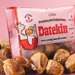 Bag of Datekin dates surrounded by sukkari dates on a pink background