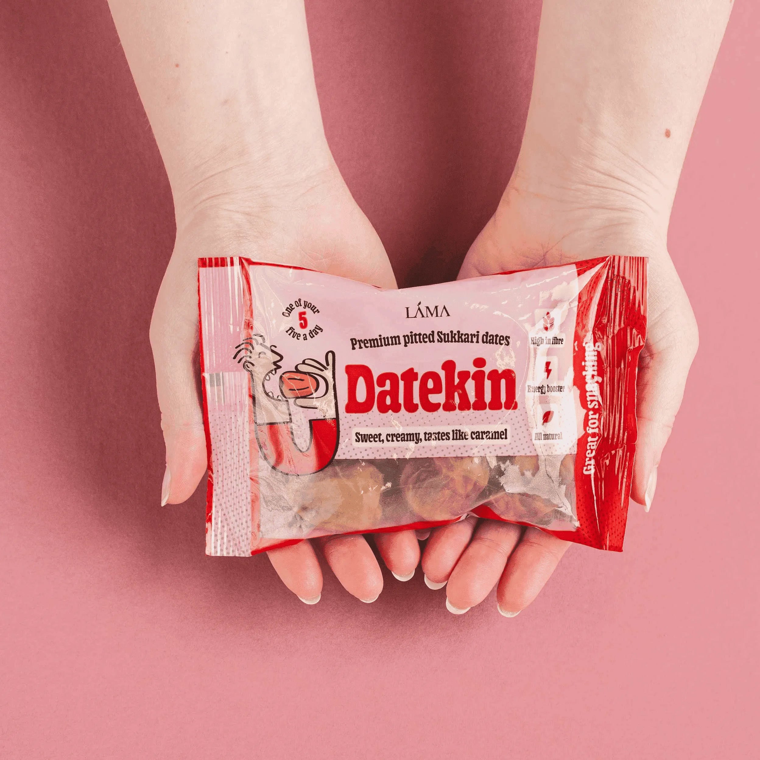 Person holding a package of Datekin against a pink background