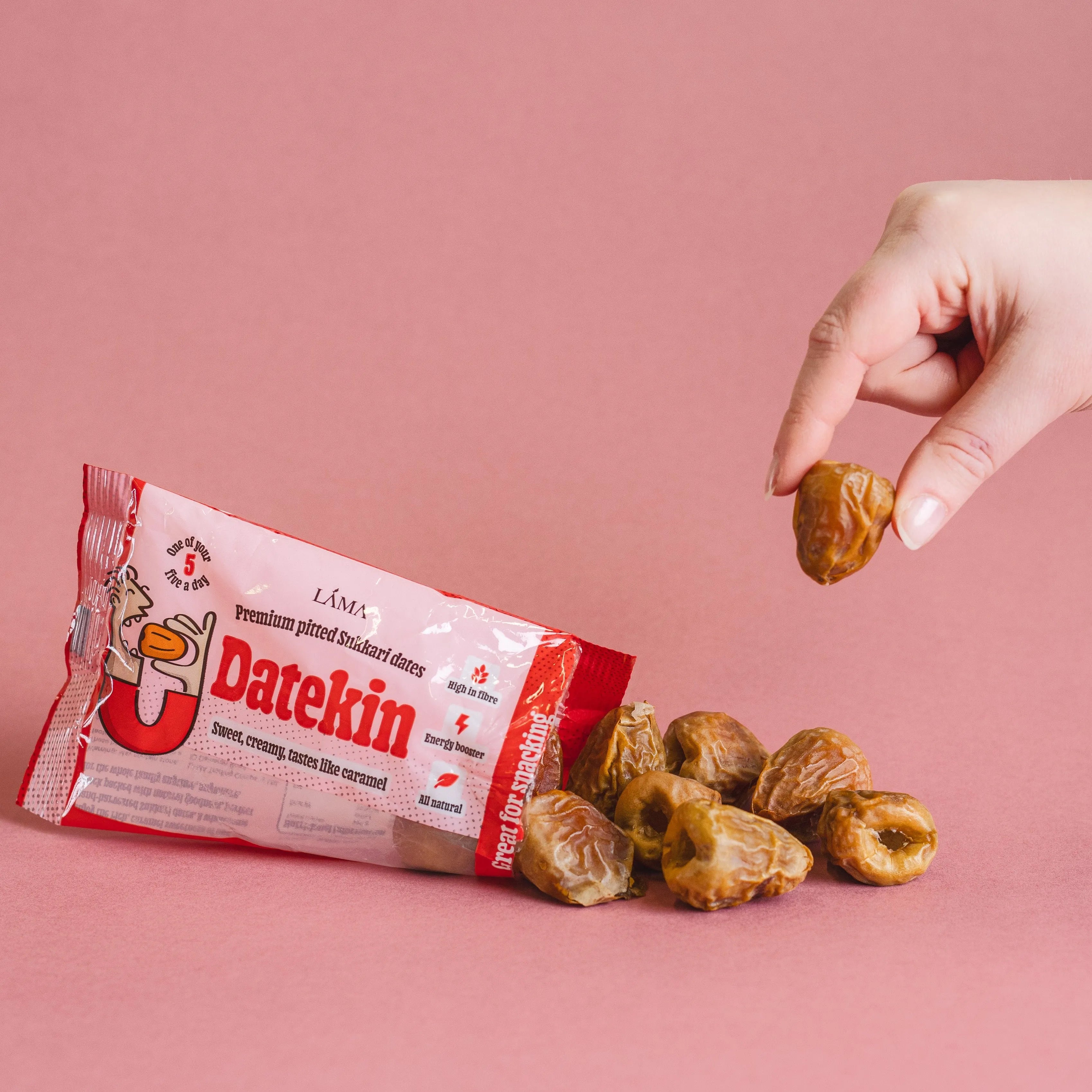 Hand holding a date above a Datekin package with dates on a pink background